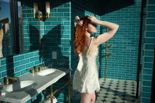 Josilee Adams, New Jersey escort, poses in an ivory silk slip in a turquoise tiled bathroom